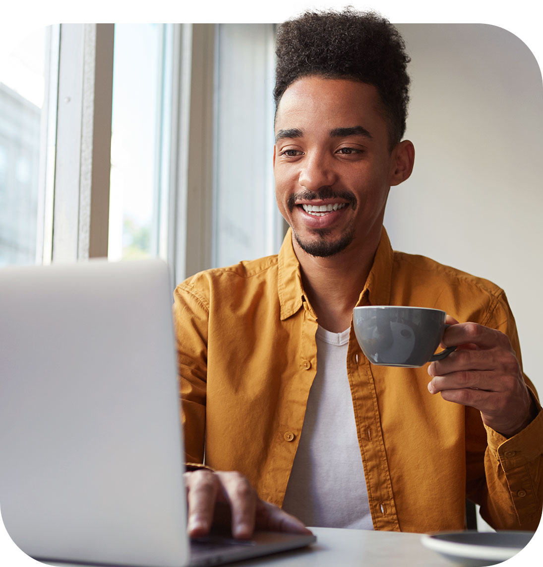 Homem trabalhando em laptop enquanto toma café