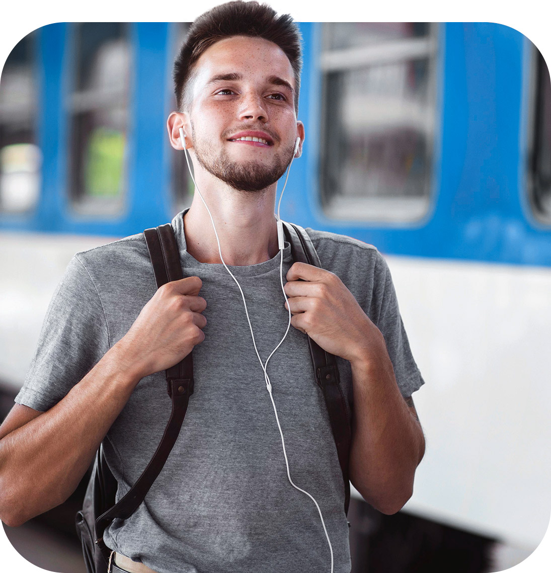 Rapaz com mochila nas costas andando ao lado de trêm em estação