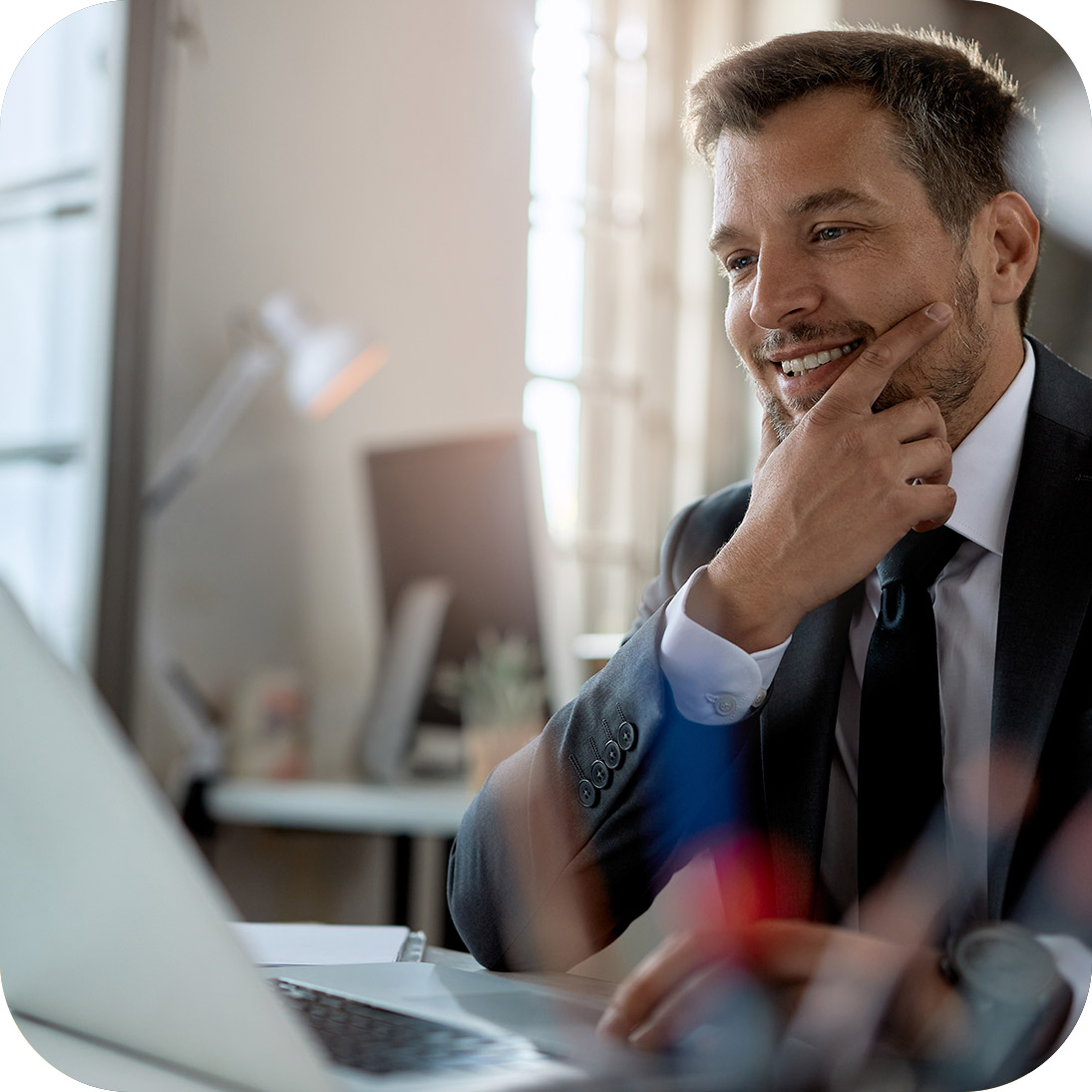 Homem sorrindo em frente a notebook no trabalho